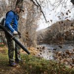 Man with leaf blower pack blowing leaves in fall